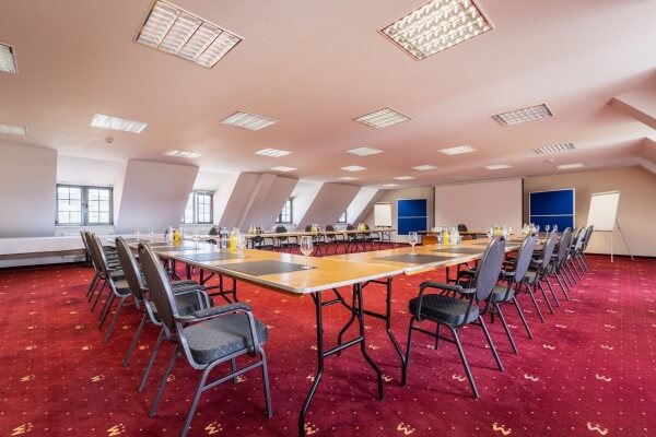 Tagungen im Konferenzsaal mit Tischen und Stühlen und einem roten Teppich.